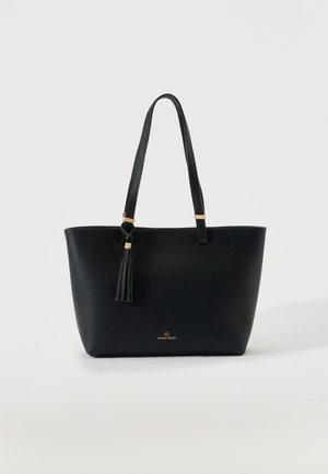 Zwarte tote tas met twee lange hengsels en een kwastdetail, klein goud logo "Anna Field" vooraan in het midden tegen een effen achtergrond.