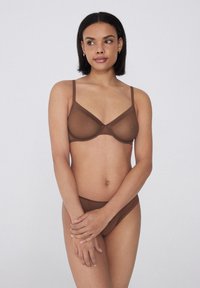 Sostenedor de malla marrón y bragas de bikini a juego. Ambos presentan tirantes finos y un diseño sin costuras. La tela parece suave con una textura transparente.