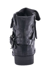Bota de tobillo de cuero negro con un acabado texturizado, que presenta correas ajustables y una suela plana. La parte trasera muestra un diseño con costuras y detalles de hardware.