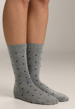 Grå sokker med mørkeblå polkaprikker, ribbede manchetter og en blød tekstur, der når til midt på læggen på bare ben.