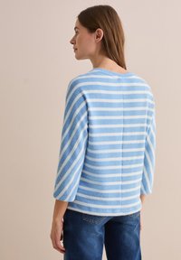 Pull rayé bleu clair et blanc en matière douce, avec des manches trois-quarts et un col rond.