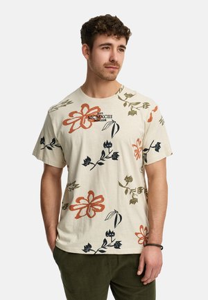 Short-sleeved beige t-shirt featuring multicolored floral patterns in orange, green, and black, with a printed logo on the chest.