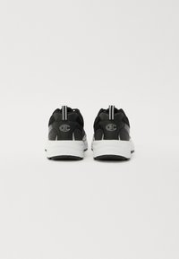 Black athletic shoes with mesh upper, padded ankle, white sole, and subtle reflective accents. Features logo on heel and pull tab.
