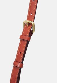 Ruskea nahkavyö kultasävyisellä soljella ja tikatuilla yksityiskohdilla. Säädettävä muotoilu sisältää useita reikiä ja sileän pintakuvion.