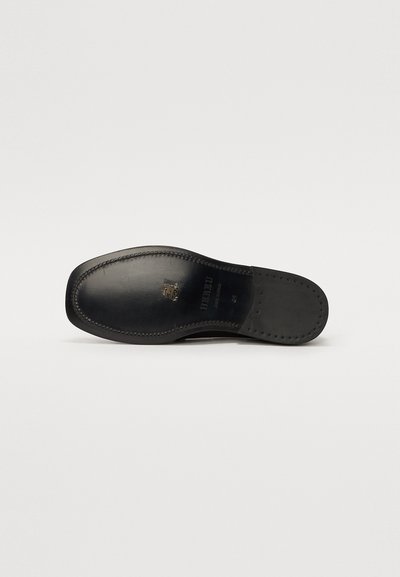 Semelle de chaussure en cuir noire, avec une finition lisse, une légère courbe à la pointe et des coutures détaillées le long du bord.