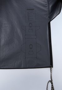 Mørkegråt stofpanel med trykt diagram af layoutet af en hættejakke og stofegenskaber, herunder tapede sømme og vandafvisende.