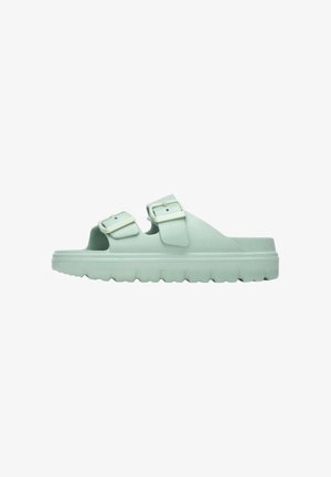 Sandalia verde menta tipo slip-on con dos tiras ajustables con hebillas y suela gruesa texturizada, mostrada de perfil sobre fondo blanco.