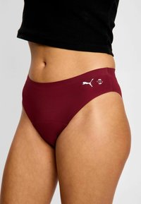 Culottes de bikini bourgogne en tissu lisse, avec une taille haute et un logo blanc Puma sur la hanche gauche. Construction sans coutures.