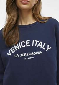 Tamno plava dukserica s bijelim natpisom "VENECIJA ITALIJA LA SERENISSIMA" i "OSNIV.421AD," sa klasičnim dizajnom okruglog izreza.