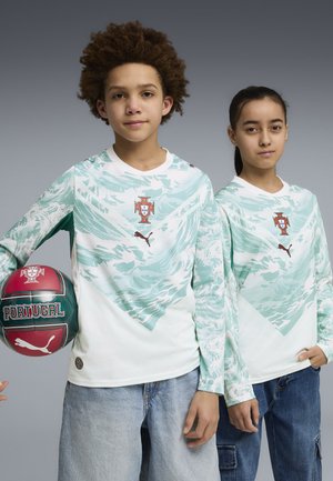 Dos jóvenes con camisetas de fútbol de Portugal con logotipos de Puma; uno sostiene un balón de fútbol de Portugal rojo y verde, ambos están de pie contra un fondo gris.