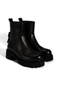 Bottines en cuir noir avec une finition texturée, semelle en caoutchouc épaisse, bout rond et languettes pour un enfilage facile. Détail à nouer à l'arrière.