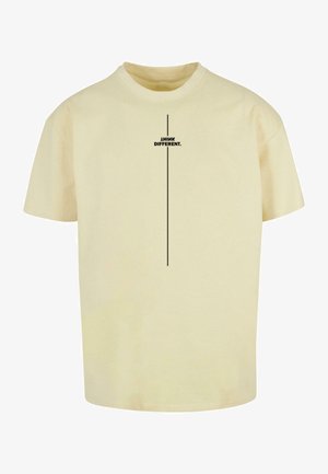 Kremowa bawełniana koszulka z krótkim rękawem, z czarnym nadrukiem "MYŚL INACZEJ." umieszczonym pionowo na przodzie.