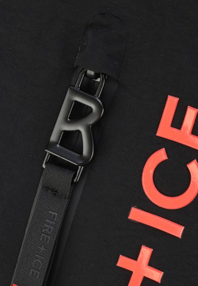 Svart tygväska med en framträdande svart spänne med en "B"-design. Ljusa korallfärgade bokstäver som stavar "FIRE+ICE" är synliga.