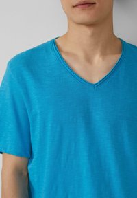 Blaues V-Ausschnitt-T-Shirt aus einem leichten, leicht strukturierten Stoff. Verfügt über ein dezentes Melange-Muster und kurze Ärmel.