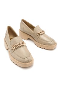Beżowe skórzane mokasyny z masywnym obcasem, z plecionym łańcuchem jako akcentem i gładką teksturą. Okrągły czubek i gumowa podeszwa dla lepszej przyczepności.