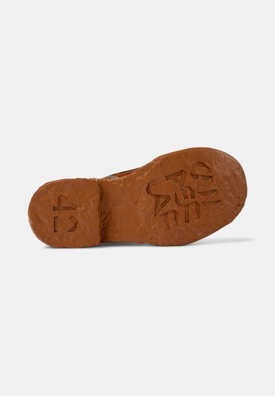 Suela de zapato de goma marrón con superficie texturizada, que presenta un diseño en relieve y números, mostrando bordes irregulares y rugosos para mayor agarre.