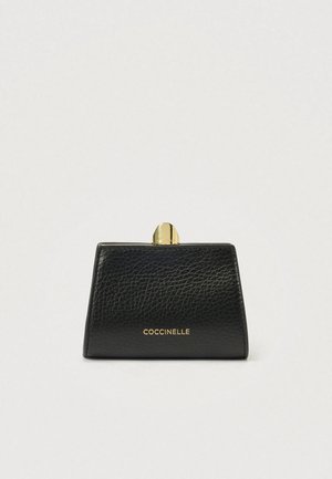 Melnas ādas rokassoma ar struktūrētu formu, zelta krāsas aizdari un iegravētu "Coccinelle" logo priekšpusē. Teksturēta virsma.
