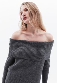 Szary sweter bez rękawów z prążkowanym wzorem, dopasowanymi rękawami i luźnym, szerokim dekoltem, oferujący elegancki fason.