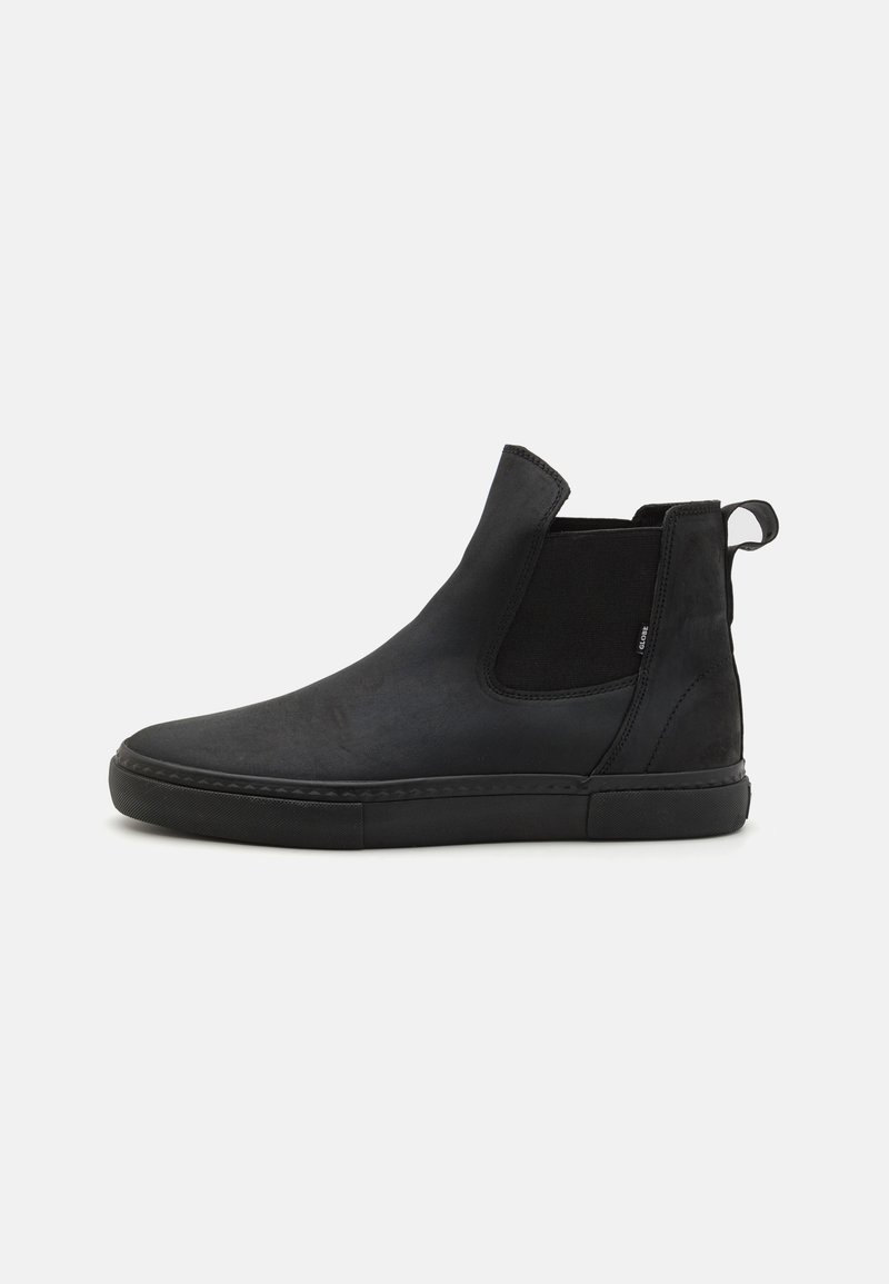 Black ankle boots made of smooth material with elastic side panels, a rounded toe, and a textured sole. Features a rear pull tab.