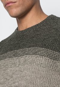 Maglione lavorato a maglia caratterizzato da un motivo testurizzato con strisce verde scuro e grigio chiaro, scollatura arrotondata e vestibilità comoda.