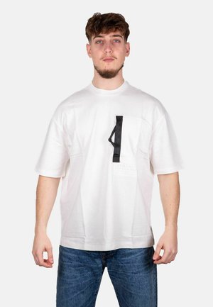 T-shirt bianco in cotone con tasca nera a contrasto caratterizzata da un design rettangolare. Maniche corte e vestibilità comoda.