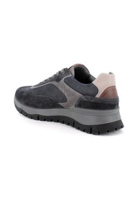 Sneaker grigie e nere con una parte superiore in suede e rete, suola in gomma spessa e un accentuato tacchetto marrone. Design con lacci.