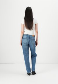Lys blå denim jeans med en avslappet passform, fem lommer og en brun merkelapp, kombinert med en tettsittende hvit t-skjorte og svarte hæler.
