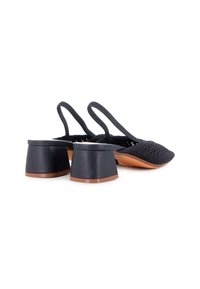 Zapatos de tirantes negros trenzados con un tacón bajo y contundente. Presentan correas entrelazadas y un diseño de punta afilada. Acabados lisos y texturizados.