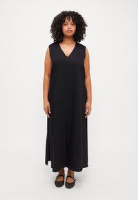 Black sleeveless maxi dress with a V-neck, featuring a front slit and a flowy A-line silhouette, made from lightweight fabric.