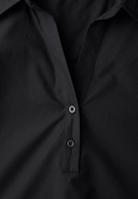 Camicia nera con colletto e bottoni, realizzata in un tessuto liscio. Presenta una parte anteriore con bottoni parziali e dettagli di cucitura sottili.