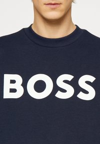 Sweatshirt azul-marinho feito de algodão, com um grande logotipo branco "BOSS" na frente, com um decote canelado e um corte casual.