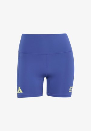 Personne portant un short Adidas bleu et des baskets blanches étire sa cuisse en tirant une jambe derrière elle, en équilibrant sur l'autre pied.