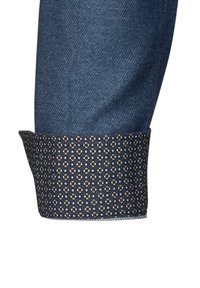 Cuff in denim con una fodera a motivi navy che presenta piccole forme a diamante in oro e azzurro chiaro, evidenziando contrasti di trame e colori.