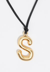 Kuldset värvi metallist ripats, mis on kujundatud tähega "S", mustal nahkvööl, millel on lihtne sõlmepuhang.