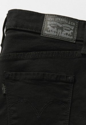 Los jeans de mezclilla negra presentan una tela texturizada, un diseño de cinco bolsillos y una etiqueta de cuero negro en la cintura con detalles en relieve.