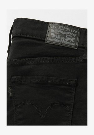 Zwarte denimjeans hebben een gestructureerde stof, een vijf-pocket ontwerp en een zwart leren logopatch op de taille met reliëfdetails.
