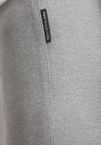Tessuto grigio in cotone misto con una texture liscia. Presenta una cucitura laterale e un'etichetta nera con la scritta "Marc O'Polo DEHIM". Design semplice e minimale.