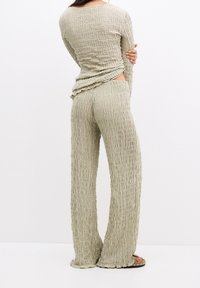 Lichtgroene textuur met een twee-delig outfit, bestaande uit lange mouwen en een brede broek, met een gekreukt stofontwerp en een open zijdetail.