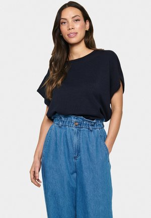 Marineblauw geribd T-shirt met korte mouwen gecombineerd met lichtblauwe high-waisted denim broek met een knoop- en elastische tailleband.