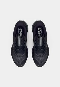 Temno sivi športni čevlji z mrežastim zgornjim delom, vzorčastimi detajli, oblazinjenim jezikom in vezalkami. Imajo oblazinjeno podplat s pikčasto zasnovo.