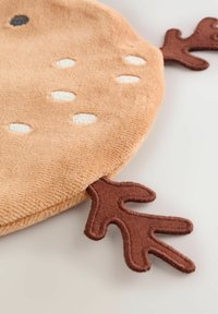 Runder, plüschiger beiger Teppich mit weißen genähten Punkten und braunen blattförmigen Akzenten. Weiche Textur und abgerundete Kanten.