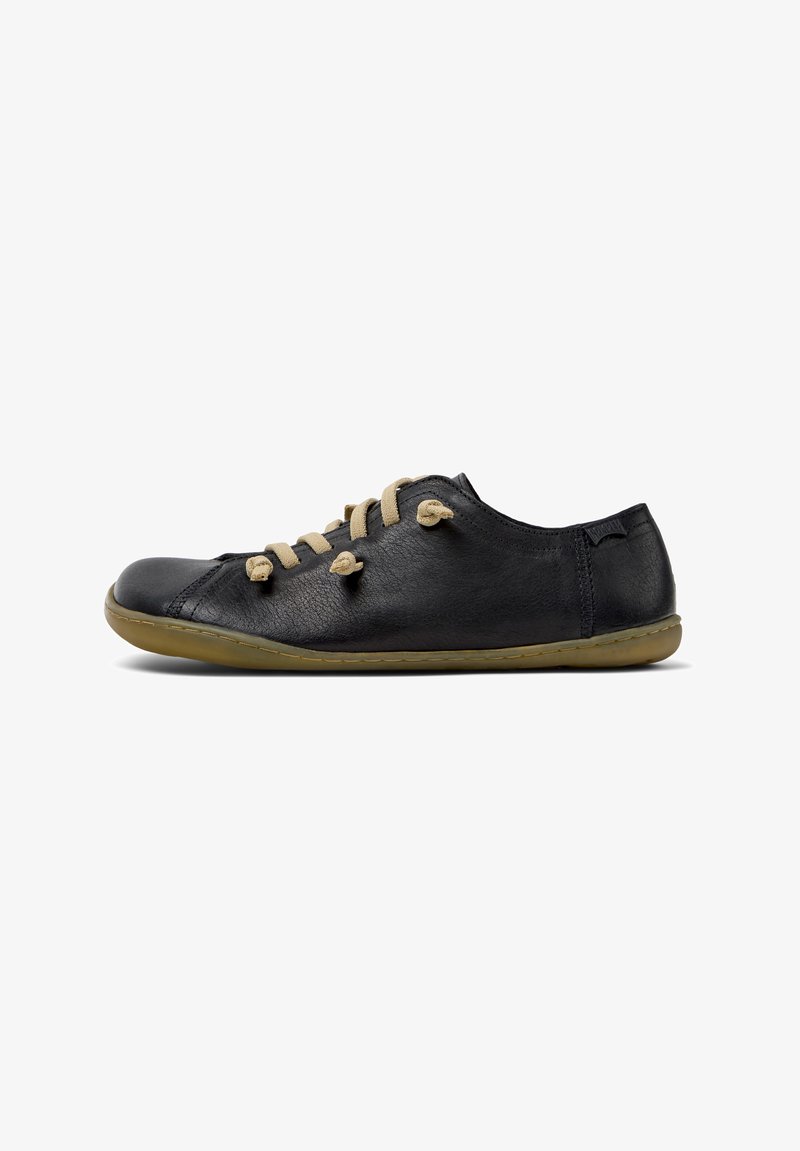 Black leather shoe with beige laces, rounded toe, flexible sole, and minimal stitching. Designed for comfort with a casual, flat silhouette.