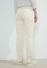 Beżowe jeansy o dopasowanym kroju z pięcioma kieszeniami, średnim stanem i lekkim rozciąganiem. Posiadają tylne kieszenie i miękką fakturę.