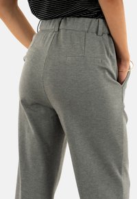 Pantaloni grigi realizzati in un tessuto morbido, con una vestibilità comoda, cintura elastica e tasche laterali. Texture sottile con una finitura liscia.