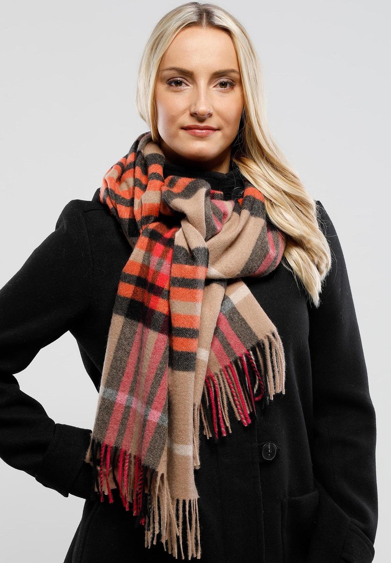 Wool scarf featuring a beige, red, and black plaid pattern with fringed edges, layered over a black coat. Soft texture, warm design.