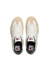 Zapatillas blancas y beige con textura de ante, que presentan una forma redondeada, sistema de cordones en la parte delantera y una etiqueta con el logo visible en la lengüeta.