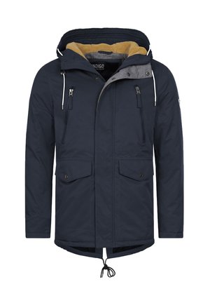 Parka blu navy con cappuccio foderato in pelliccia, due tasche con zip e due tasche con bottoni a pressione, orlo regolabile con coulisse e fodera interna grigia. Materiale impermeabile.