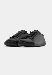 Mustat nahkakengät pyöreällä kärjellä, joissa on hillitty ompelu, litteät nauhat ja joustava kumipohja. Minimalistinen muotoilu ja sileä pinta.