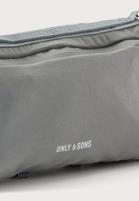 Pochette en tissu gris avec une fermeture éclair et le logo "ONLY & SONS" imprimé en blanc sur le devant.