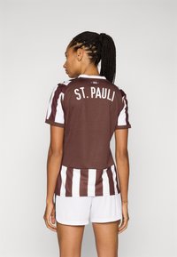 Brown and white striped soccer jersey with "ST. PAULI" printed on the back, paired with white shorts. Short sleeves, breathable fabric.